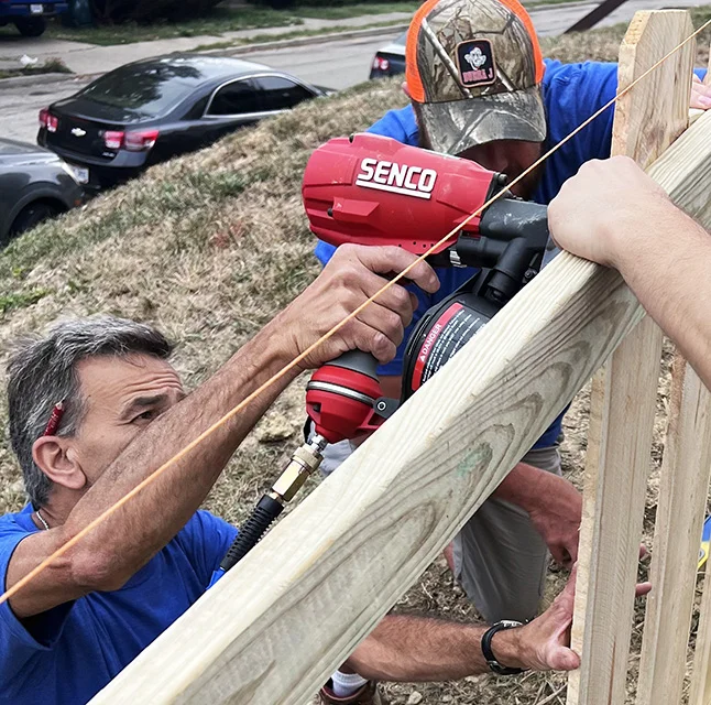 Individual using SENCO coil nailer to fasten fence boards